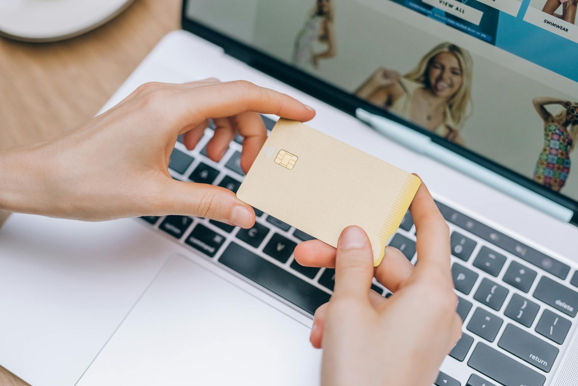 Hands holding credit card over laptop keyboard demonstrating online shopping performance considerations for Australian e-comm