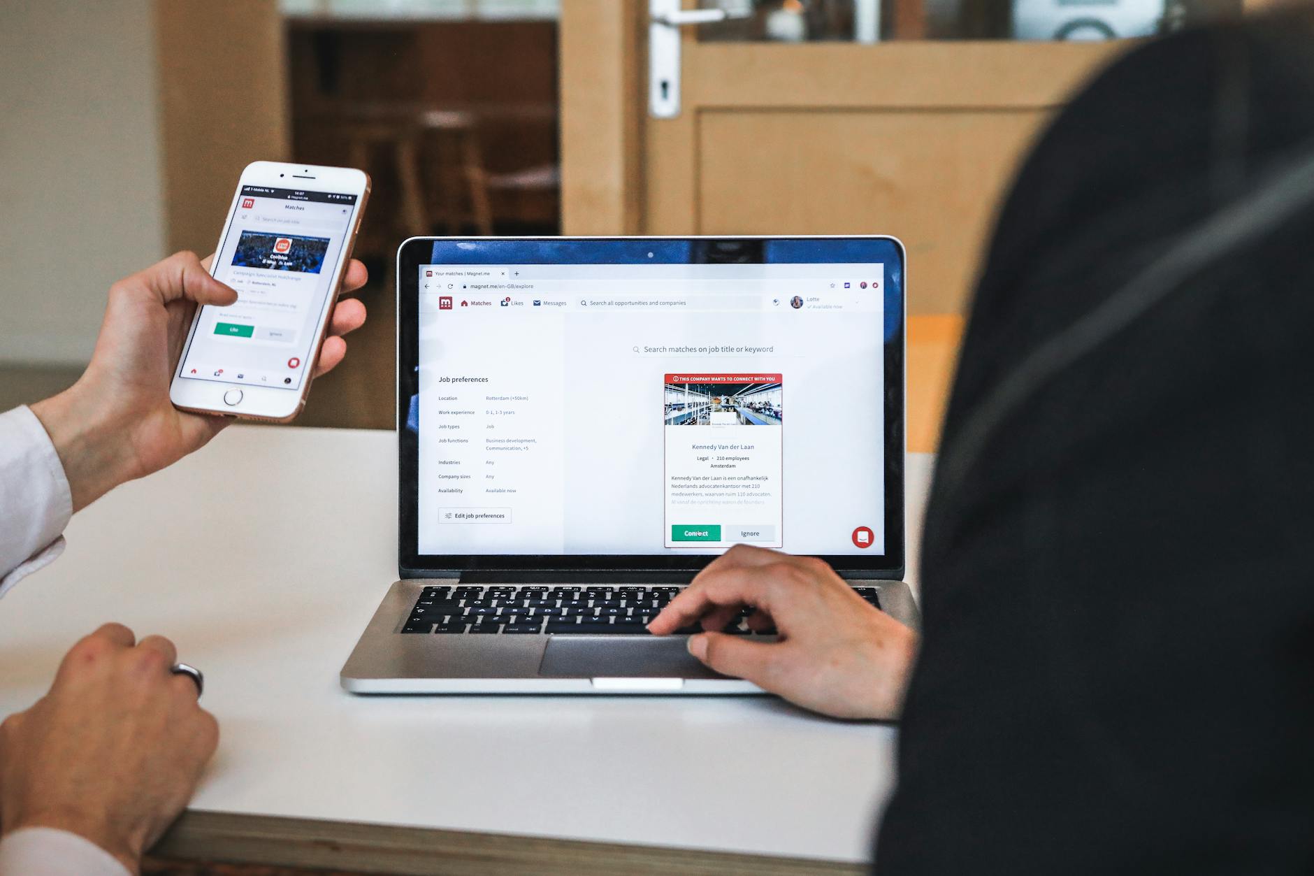 Small business owner checking website performance metrics on laptop and smartphone in modern office workspace