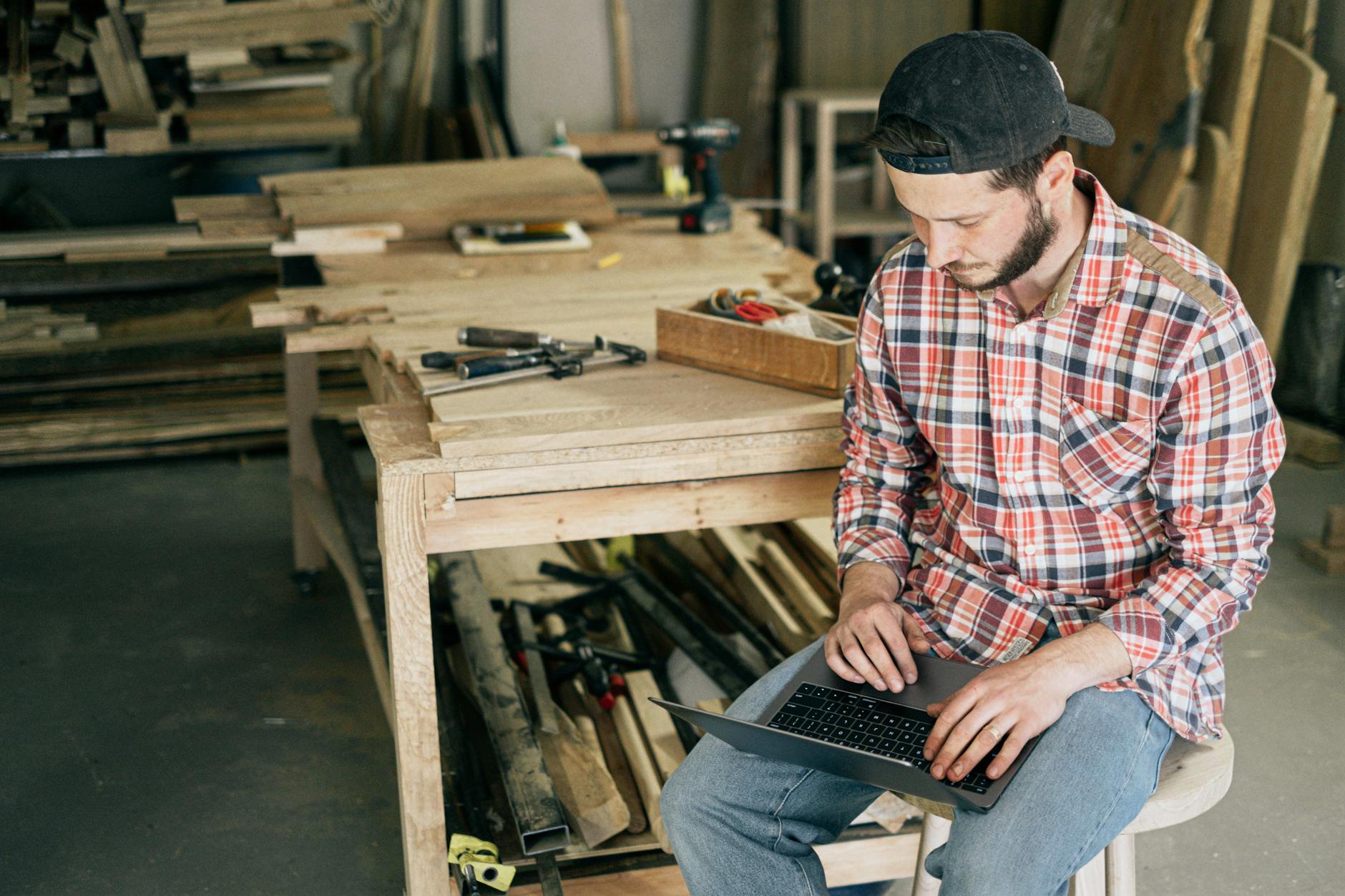 Skilled tradesperson building their online presence on a laptop in a workshop setting